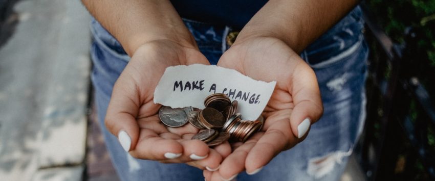 Hands holding coins with a note that says Make a Change