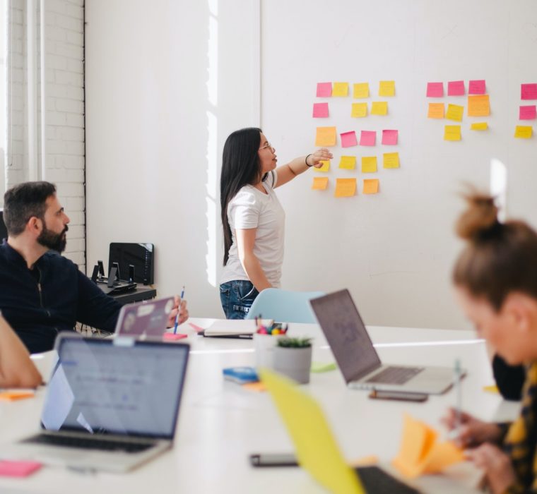 woman at front of room pointing to whiteboard